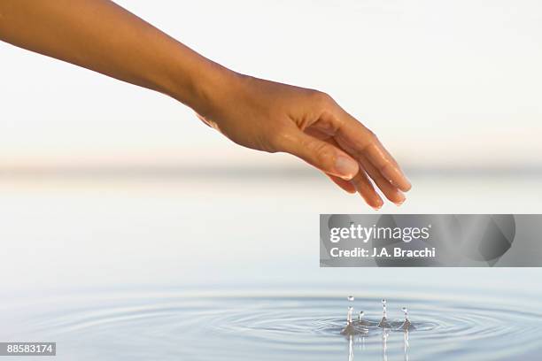 woman lifting hand from pool of water - swimming pool and hand stock-fotos und bilder