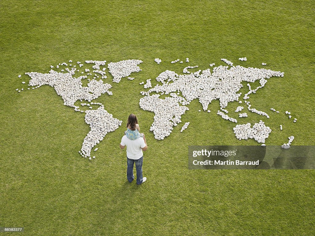 Father and daughter looking at world map made of rocks