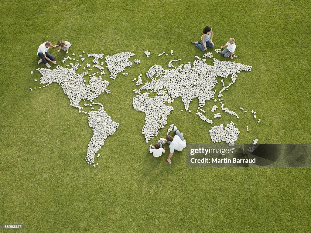 Parents and children making world map made of rocks
