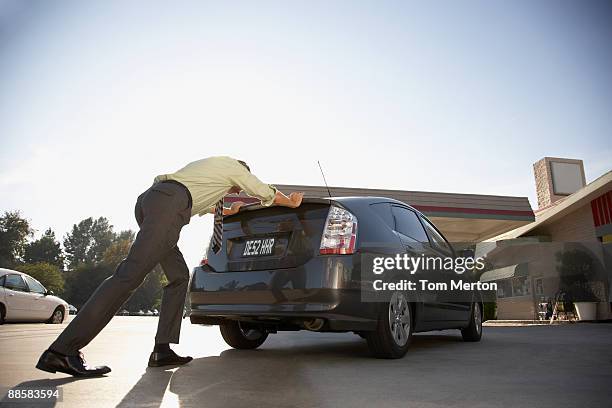 man pushing car into service station - man pushing stock pictures, royalty-free photos & images