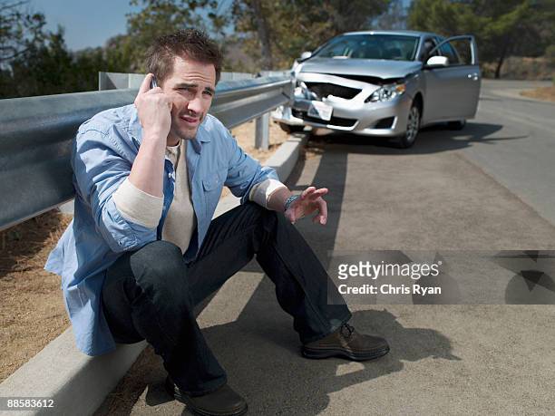 man with crashed car calling for roadside assistance, - car accident stock pictures, royalty-free photos & images