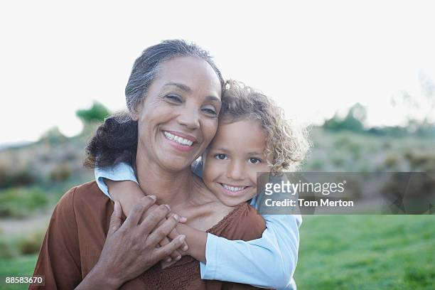 boy hugging grandmother - multiracial person stock pictures, royalty-free photos & images