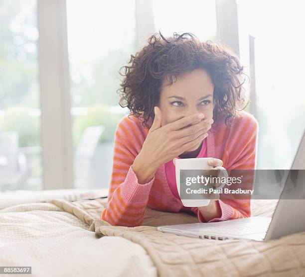 woman looking at laptop in bed - romance cover stock pictures, royalty-free photos & images