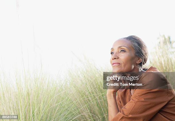 serene woman sitting in sunny field - black woman field stock pictures, royalty-free photos & images