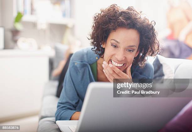 woman using laptop on sofa - bradbury house stock pictures, royalty-free photos & images