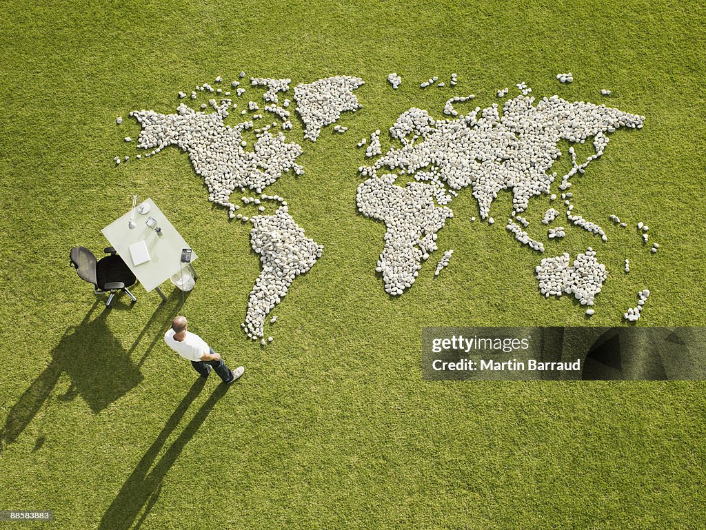 Businessman working near world map made of rocks