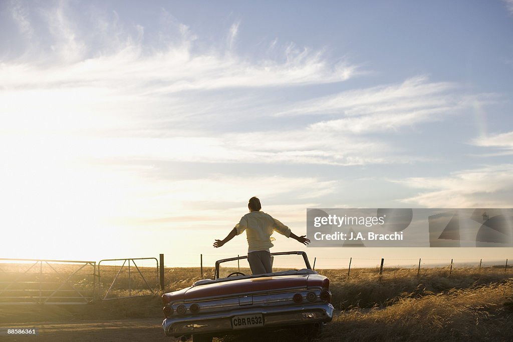 Man standing in convertible in countryside