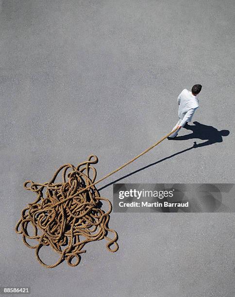 businessman pulling tangled rope - sleep walking stockfoto's en -beelden