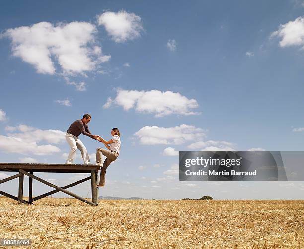 man helping woman up wooden dock in field - 引く ストックフォトと画像