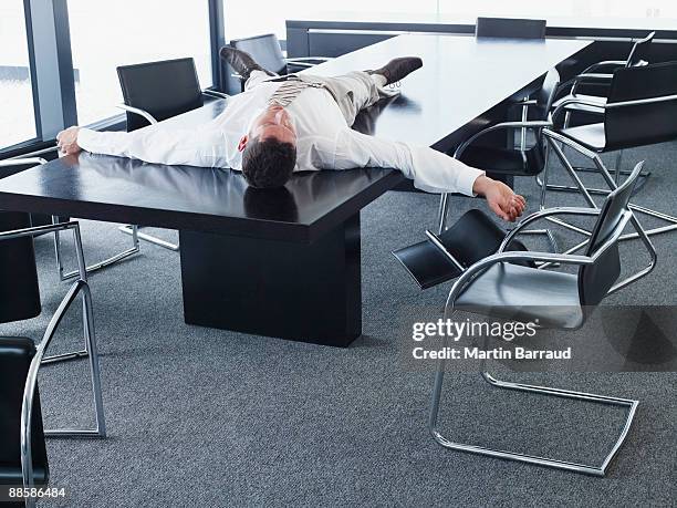 businessman lying on conference table - overdoing stock pictures, royalty-free photos & images