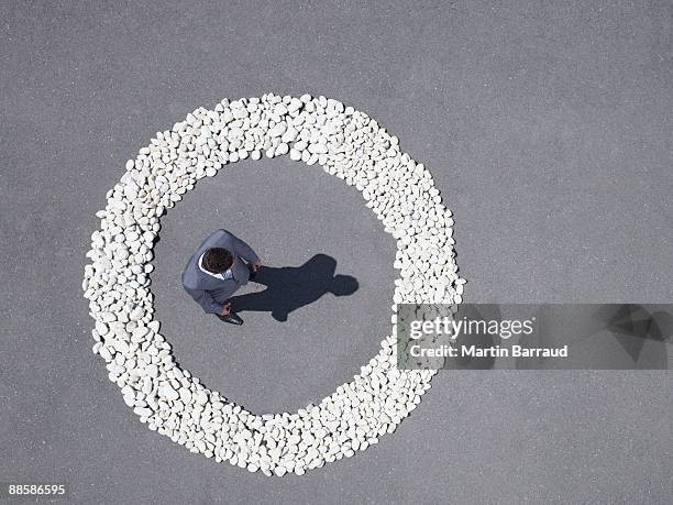 businessman standing inside rock circle - entourer photos et images de collection