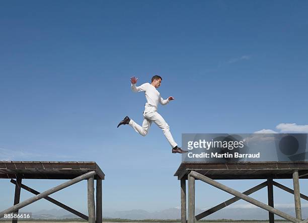 man jumping over gap - achievement gap stock pictures, royalty-free photos & images