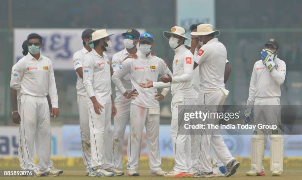 Sri Lanka's players gathers wearing anti-pollution masks during the second day of their third test cricket match in New Delhi.