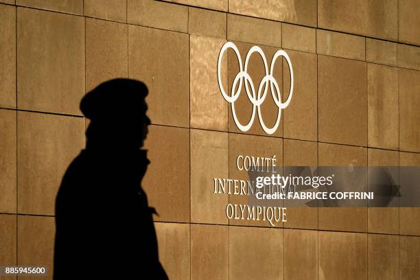 Private guards is seen in silhouette in front of the International Olympic Committee at their headquarters prior to an executive meeting on December...