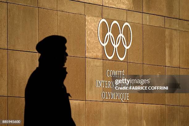 Private guards is seen in silhouette in front of the International Olympic Committee at their headquarters prior to an executive meeting on December...