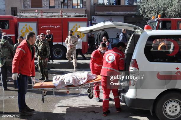 Members of the Syrian Arab Red Crescent load a body into an ambulance following a car bomb explosion in a predominantly pro-government neighbourhood...