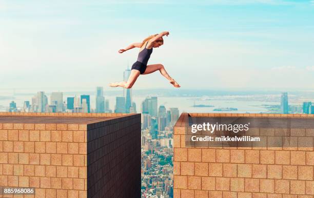 vrouw maakt het gevaarlijk sprong via een kloof tussen twee hoge gebouwen - parkour building stockfoto's en -beelden