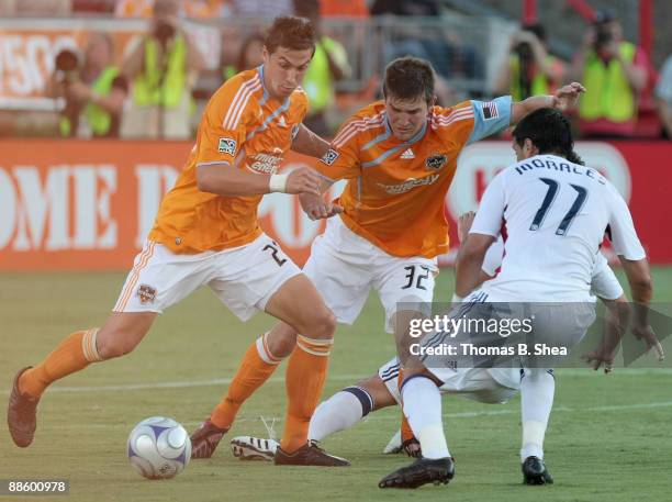 Geoff Cameron and Bobby Boswell of the Houston Dynamo try to dribble the ball past Javier Morales of Salt Lake Real at Robertson Stadium on June 20,...