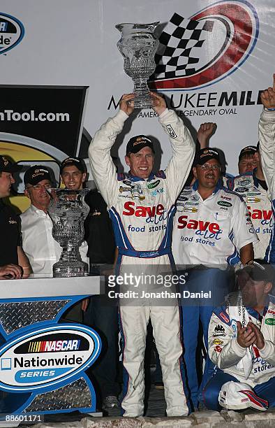 Carl Edwards, driving the Save-a-lot Ford, holds the trophy and celebrates a win at the NASCAR Nationwide Series NorthernTool.com 250 on June 20,...