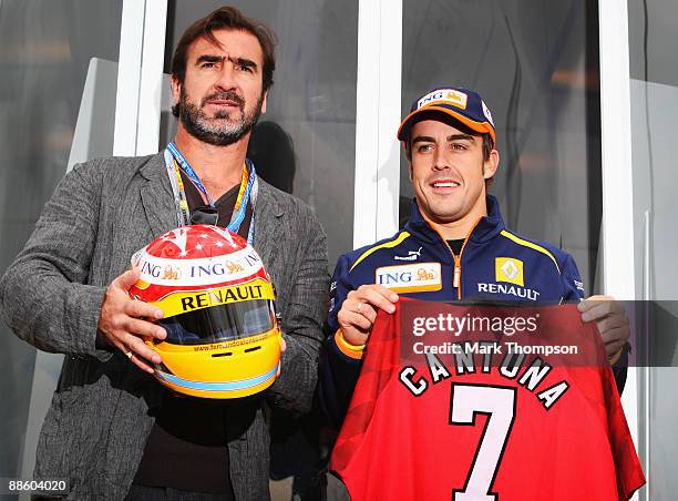 Former Manchester United and French international footballer Eric Cantona and Fernando Alonso of Spain and Renault are seen in the paddock before the...