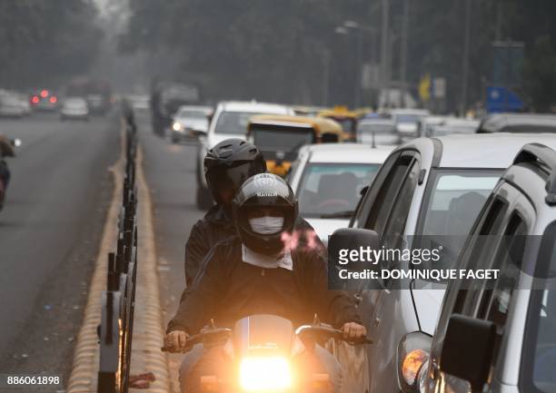 An Indian motorcyclist wearing face protection against air pollution rides on the road amid heavy smog in New Delhi on December 5, 2017. The United...