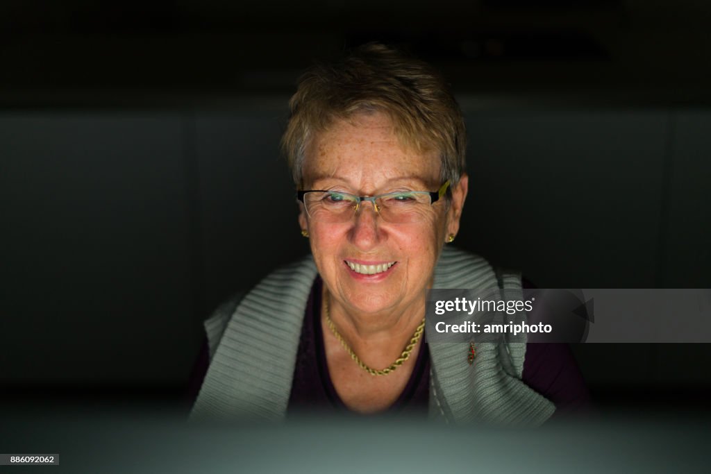 Senior Portrait - happy laughing senior woman looking at computer screen