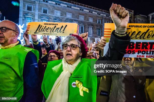 Pro independence woman, member of the safety of the event, raises the arm with a clenched fist, while singing the catalan national anthem....