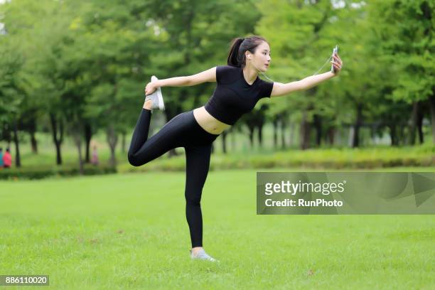 young woman doing yoga and listening to music - lord of the dance pose stock pictures, royalty-free photos & images