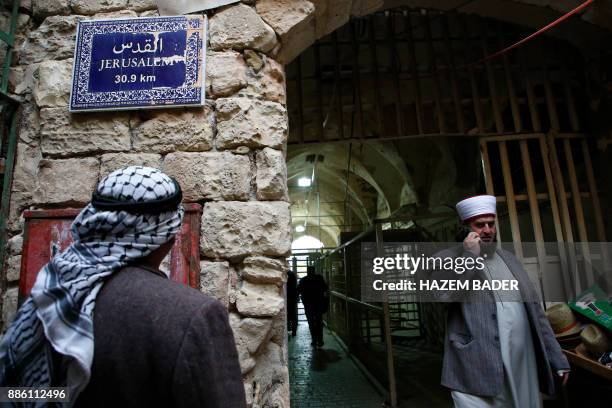 Palestinian men walk past a street sign indicating the distance to Jerusalem on December 5 in Hebron in the Israeli-occupied West Bank.