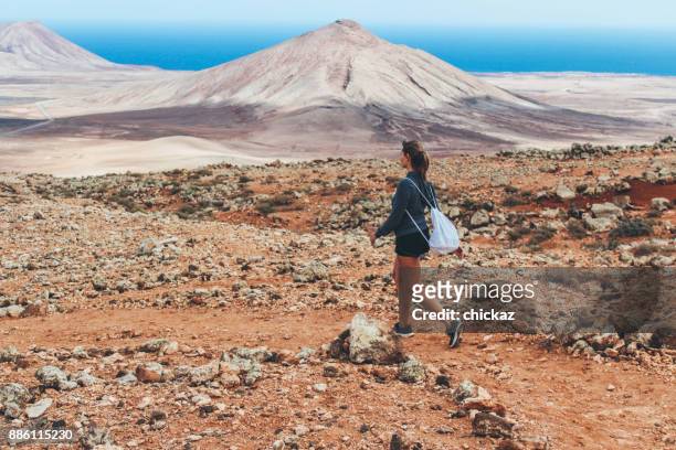 ung kvinna vandring med panoramautsikt över vulkanen - fuerteventura bildbanksfoton och bilder