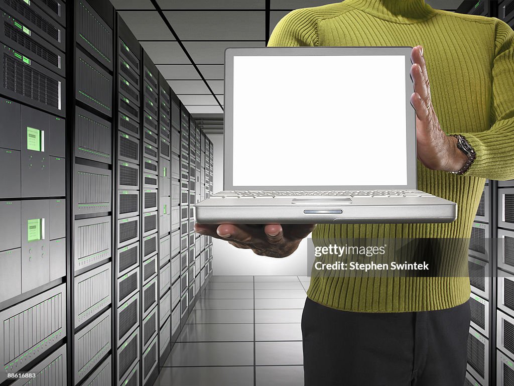 Man holding a laptop in a server room