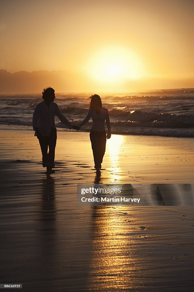 Silhoutte of Asian couple walking along beach