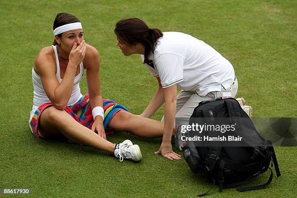 Severine Bremond Beltrame of France is assisted as she is injured during the women's singles first round match against Victoria Azarenka of Belarus...