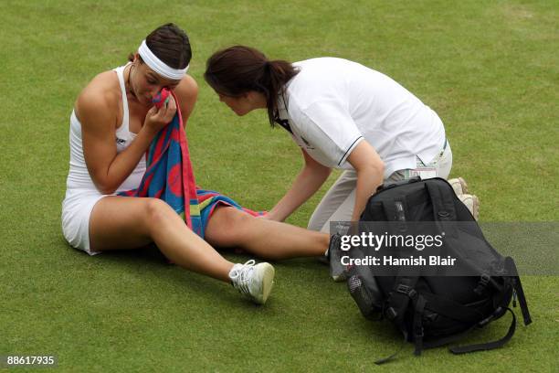 Severine Bremond Beltrame of France is assisted as she is injured during the women's singles first round match against Victoria Azarenka of Belarus...