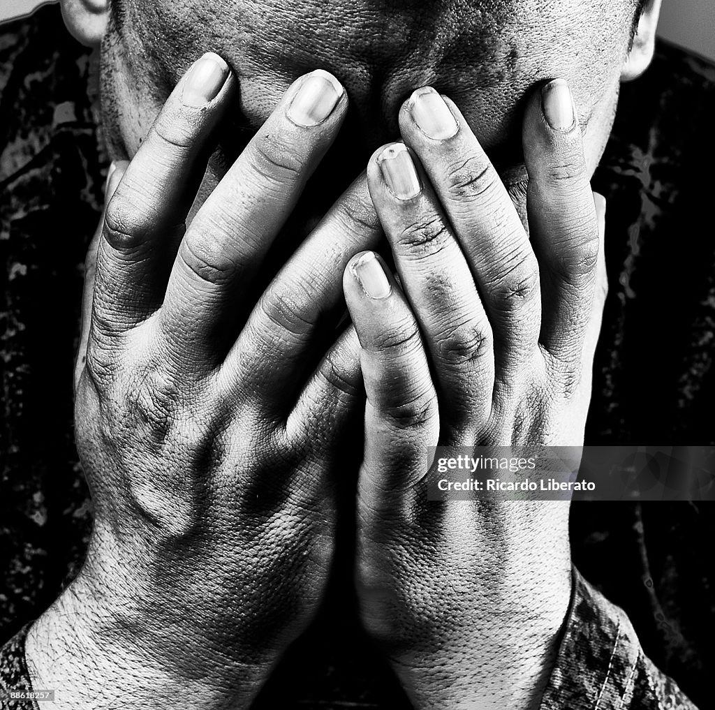 Depressed man, hands covering face