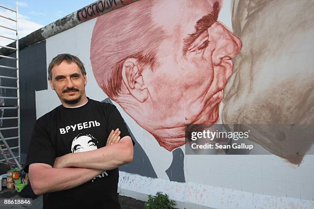 Russian artist Dmitry Vrubel poses in front of his work in progress showing former Soviet leader Leonid Brezhnev kissing former communist East German...