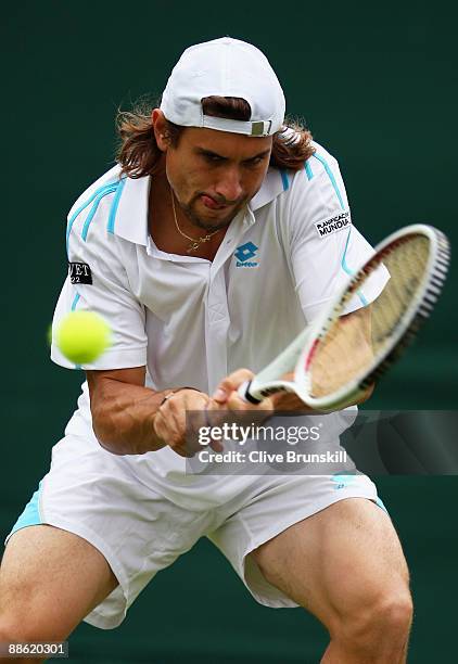 David Ferrer of Spain plays a backhand playing with Marc Lopez of Spain during the men's doubles first round match against Jeff Coetzee of South...