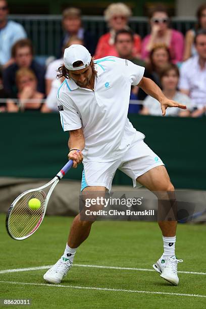 David Ferrer of Spain plays a forehand playing with Marc Lopez of Spain during the men's doubles first round match against Jeff Coetzee of South...