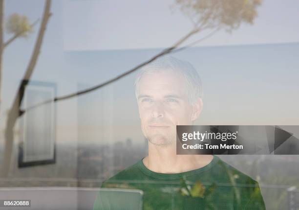 uomo guarda fuori soggiorno finestra - uomini di età media foto e immagini stock
