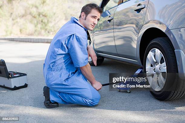 mechanic changing cars flat tire - jacke stock pictures, royalty-free photos & images