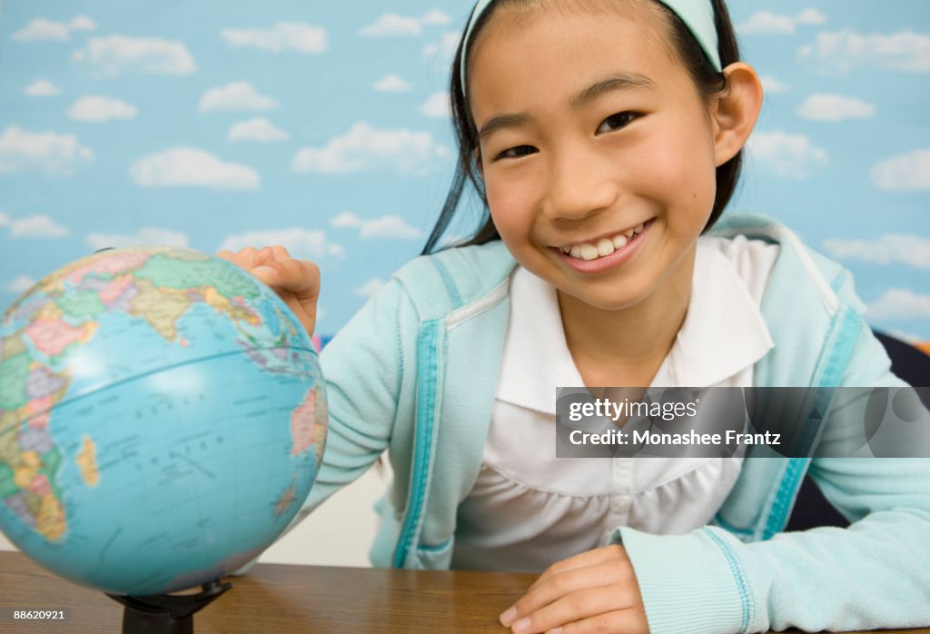 Girl looking at globe in classroom