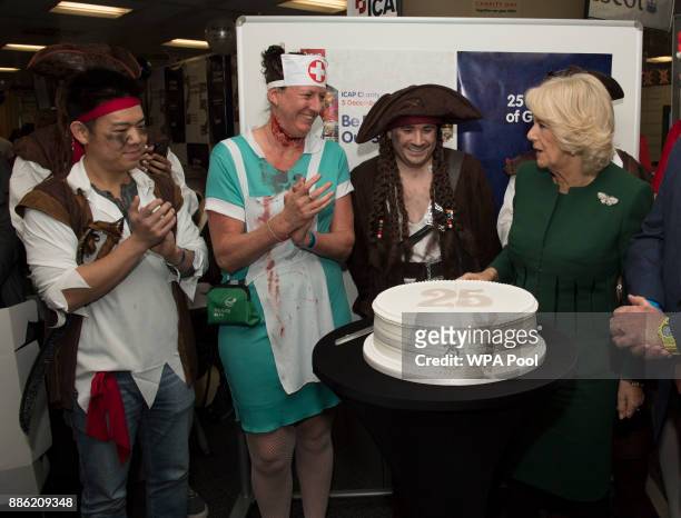 Camilla, Duchess of Cornwall, Patron, Medical Detection Dogs, cuts a cake to mark ICAP's 25th year during her visit to ICAP during the broker's...