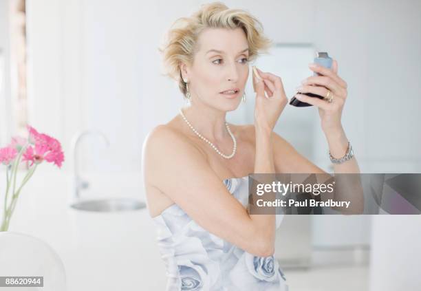 mujer poniendo maquillaje de fiesta - vestido de fiesta fotografías e imágenes de stock