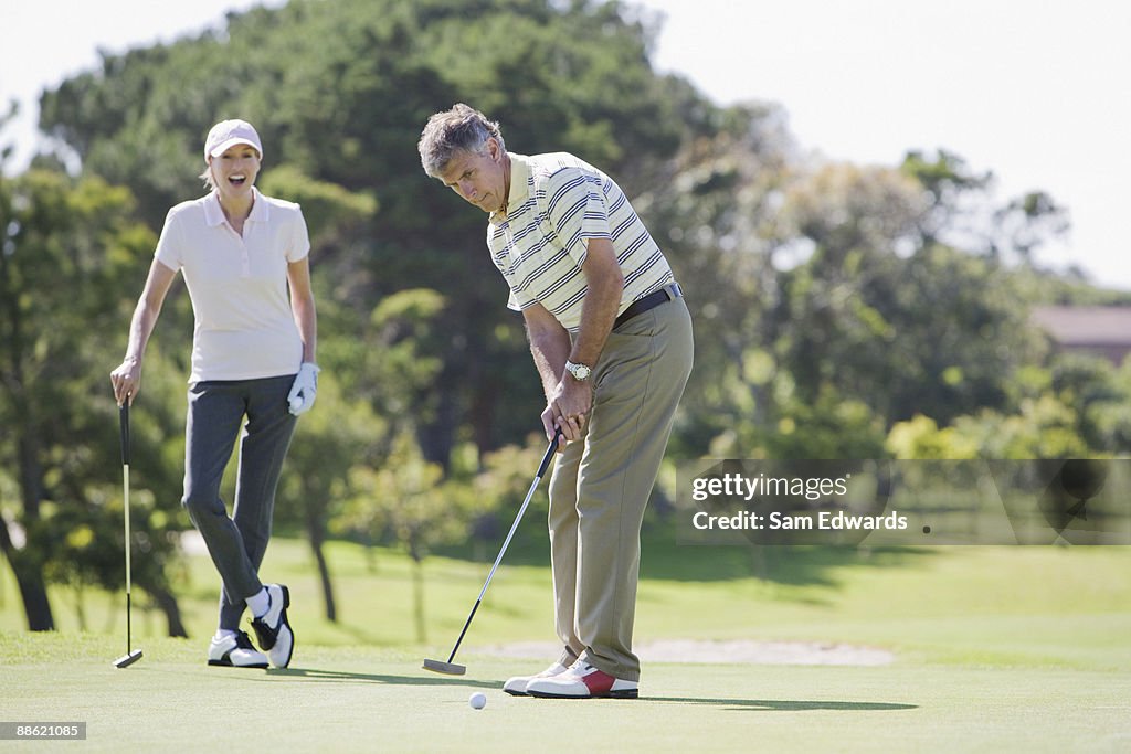 Mature couple playing golf together