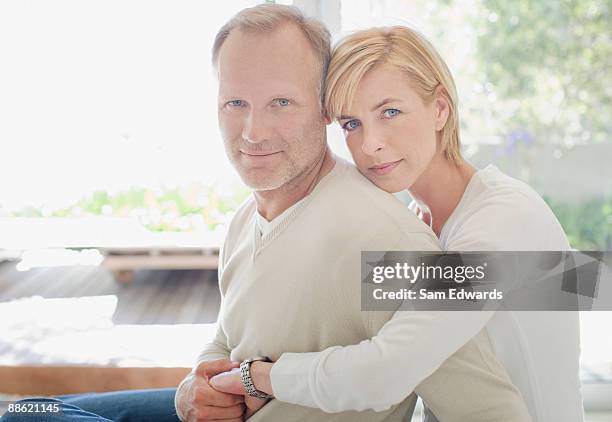 couple hugging in living room - serious couple stock pictures, royalty-free photos & images