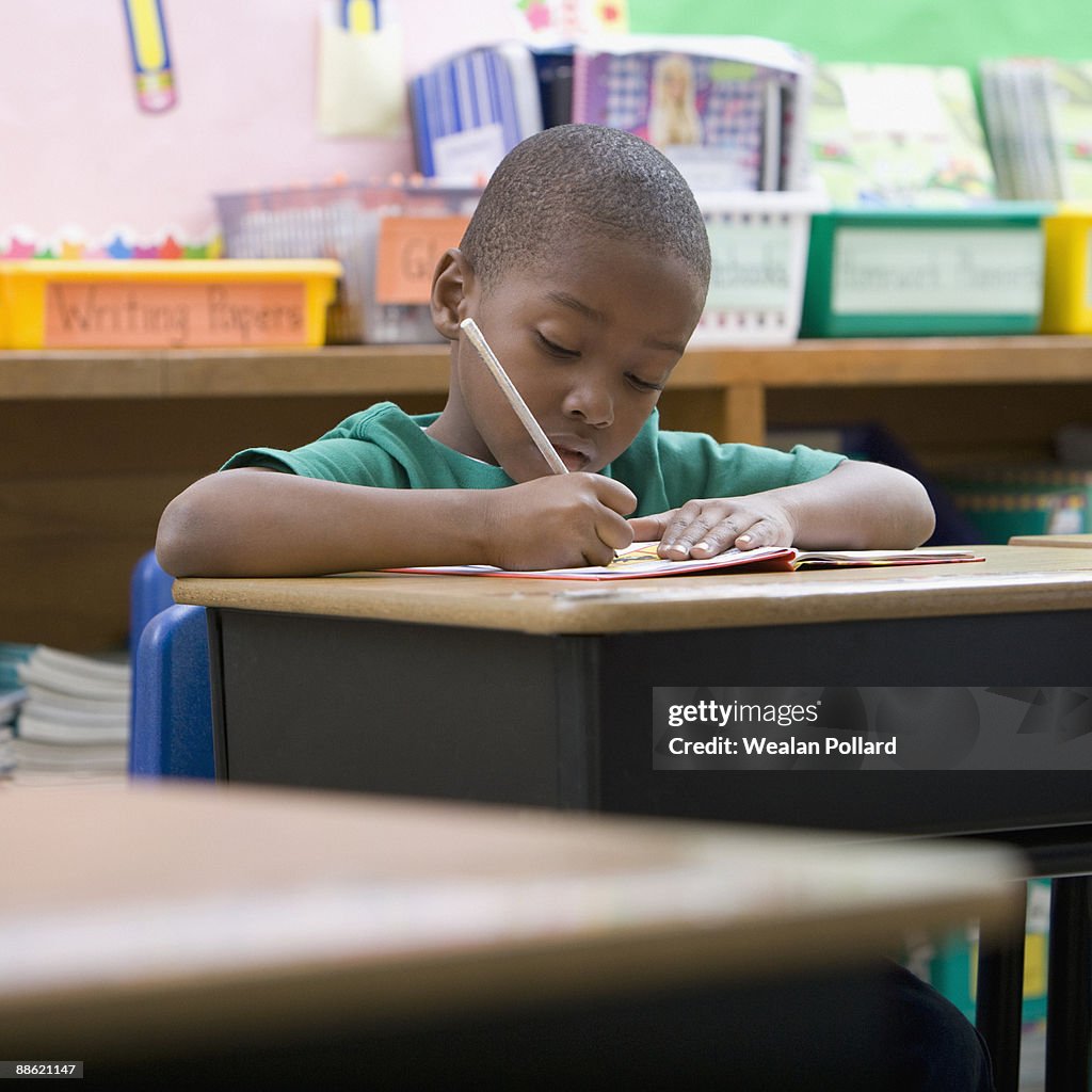 Boy doing school work at desk in classroom