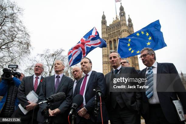 Democratic Unionist Party Deputy Leader Nigel Dodds speaks to members of the media as a protester waves flags outside the Houses of Parliament on...