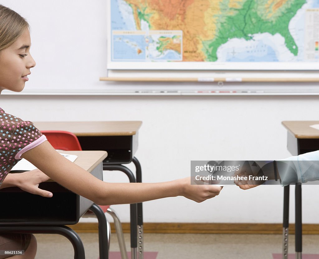 Girl passing note in classroom