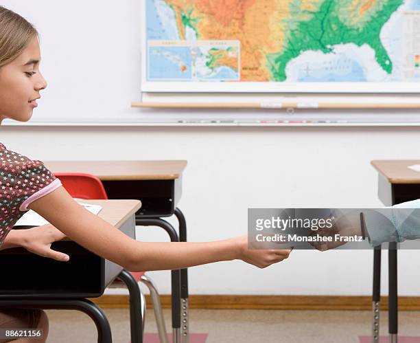 girl passing note in classroom - receiving paper stock pictures, royalty-free photos & images