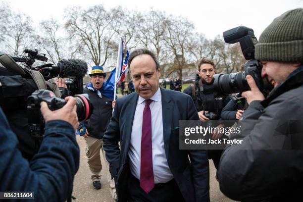 Democratic Unionist Party Deputy Leader Nigel Dodds leaves after speaking to members of the media as a protester holding flags shouts after him...